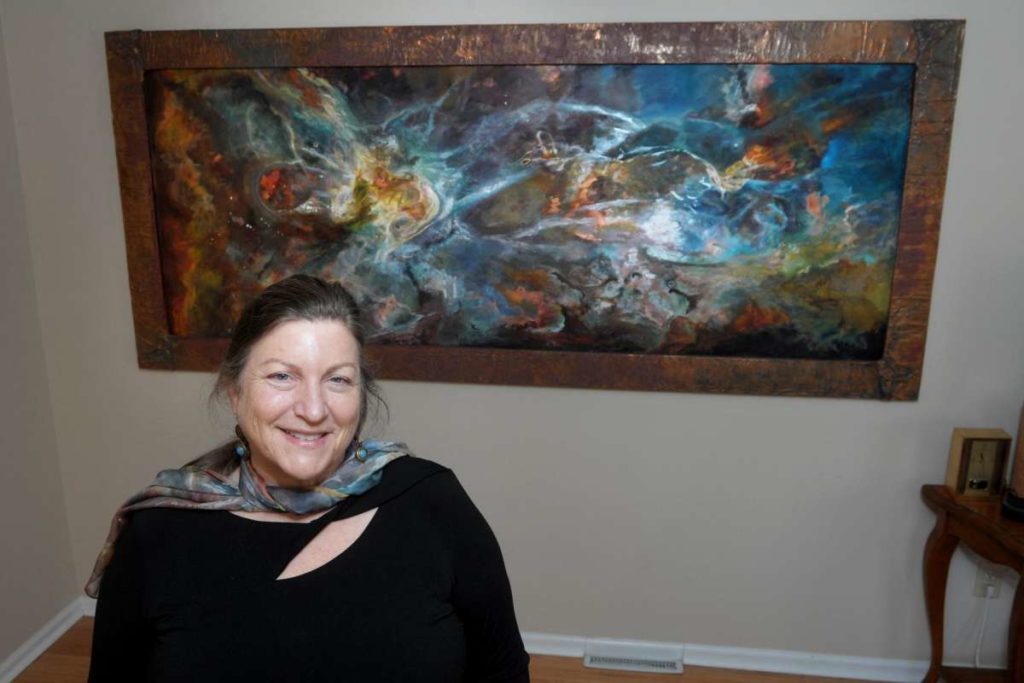 Jill Nichols poses in front of her painting ‘Phi’ in her home and studio in Shelton, Conn. Jan. 22, 2021. A copy of the painting currently hangs in the Vatican Observatory Museum